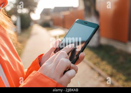 Il concetto di smartphone e Internet. Le mani delle donne stanno tenendo uno smartphone, e qualcosa sta digitando su di esso. In background, la traccia va Foto Stock