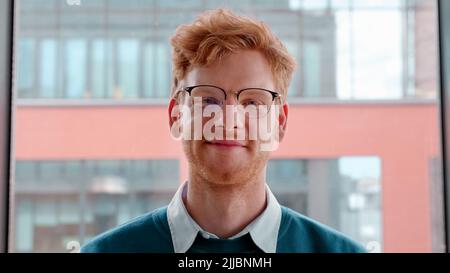 Giovane zenzero irlandese in occhiali che incrociano le mani sul petto ritratto Foto Stock