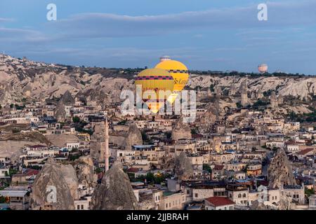 GOREME/TURCHIA - 29 giugno 2022: I palloncini ad aria calda volano a bassa velocità sulla città di goreme. Foto Stock