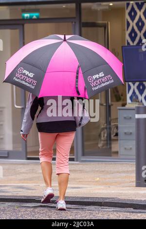 Ombrello da golf Black & Mauve Ping a Preston, Lancashire. Meteo Regno Unito 25 luglio 2022. Un inizio umido alla giornata a Fishergate. Preston High Street, negozi e negozi di moda estiva nel centro della città in una giornata estiva. Credit; MediaWorldImages/AlamyLiveNews Foto Stock