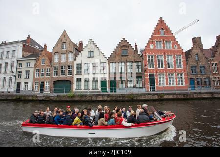 La gente visita la città di Brugges, Belgio, da tour in barca che opera attraverso la rete dei canali della città Foto Stock