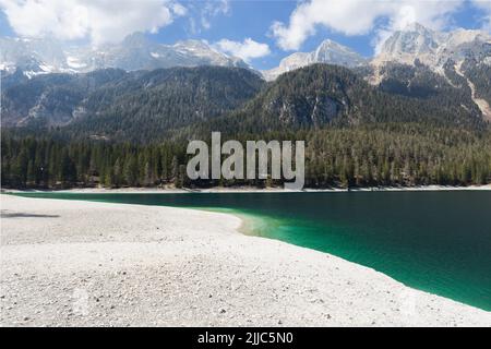 Dolcemente spiovente costa rocciosa di un lago Tovel color smeraldo alto sulle montagne e un crinale di alte cime alpine. Ville d'Anaunia, Trentino, Italia Foto Stock