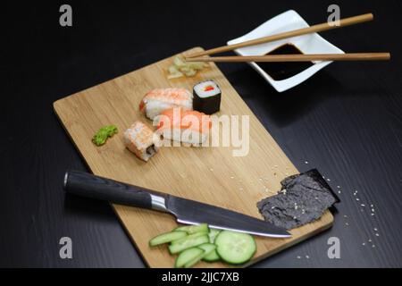Un primo piano di diversi tipi di sushi con ingredienti su un tagliere Foto Stock