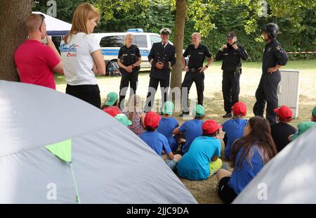 Malchow, Germania. 25th luglio 2022. Varie uniformi di polizia sono presentate ai bambini durante la giornata di azione della polizia e dei vigili del fuoco al campo all'aperto della polizia di Stato di Meclemburgo-Pomerania occidentale 2022. 68 bambini, di cui 15 provenienti dall'Ucraina, partecipano al campo di vacanza della durata di una settimana presso la Scuola Statale di protezione contro incendi e disastri del Meclemburgo-Pomerania occidentale. Il campo libero è destinato a bambini tra i 11 e i 13 anni provenienti da famiglie socialmente svantaggiate. Credit: Bernd Wüstneck/dpa/Alamy Live News Foto Stock