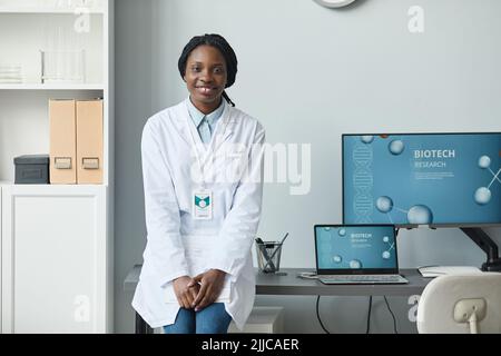 Ritratto di giovane donna nera sorridente alla macchina fotografica mentre lavora in laboratorio di ricerca, spazio copia Foto Stock