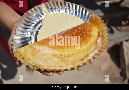 Un'immagine selettiva di fuoco delle donne che tiene un ghee appena fatto Masala DOSA Roosted in mano Foto Stock