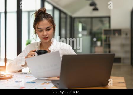 Donna che parla di grafici di analisi o grafici su un tavolo da lavoro e utilizza un computer portatile. Primo piano analisi femminile e concetto di strategia. Foto Stock