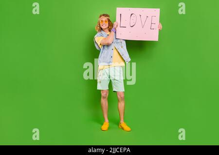 Foto del corpo intero di persona allegra positiva tenere carta carta amore carta isolato su sfondo verde Foto Stock