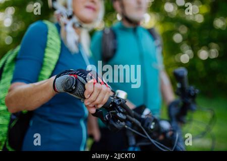 Primo piano di una coppia senior che guida le biciclette, una donna che tiene il manubrio. Foto Stock