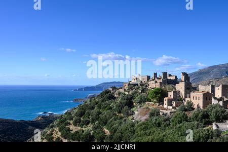 Le torri di pietra e le case in rovina di Vathia con la costa drammatica del mani profondo sullo sfondo, peloponneso meridionale, Grecia. Foto Stock