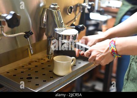 Le mani della donna fanno il caffè con un portafiltro Foto Stock