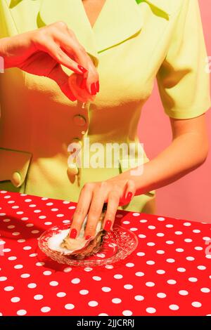 Immagine colorata di mano femminile che spreme il limone su una deliziosa ostrica isolata su tovaglia rossa Foto Stock