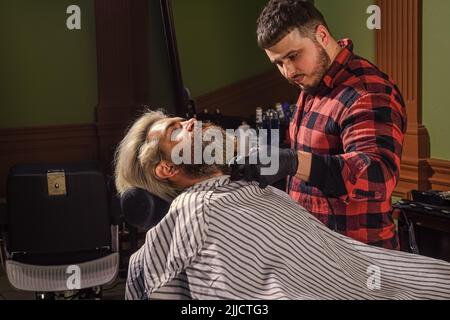 Barber è una risorsa essenziale per il vostro stile. Rasatura con il rasoio. Capelli del viso. Mantenere la forma della barba. Fai crescere barba e baffi. Uomo al barbiere Foto Stock