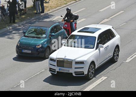 Monaco di Baviera, Germania. 22nd luglio 2022. Immagine a tema GRANDE VS PICCOLA. Un SUV di lusso Rolls Royce Cullinan guida accanto a una Fiat 500 piccola auto, dietro di esso guida uno scooter su una strada a Monaco di Baviera su 22.07.2022 ?SVEN SIMON Fotoagentur GmbH & Co. Pressedoto KG # Prinzess-Luise-Str.. 41 # 45479 M uelheim/R uhr # Tel. 0208/9413250 # Fax. 0208/9413260 # GLS Bank # BLZ 430 609 67 # conto 4030 025 100 # IBAN DE75 4306 0967 4030 0251 00 # BIC GENODEM1GLS # www.svensimon.net. Credit: dpa/Alamy Live News Foto Stock