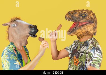 Uomo in dinosauro animale testa maschera e donna con testa di cavallo mangiare gelato al cioccolato isolato su sfondo giallo con spazio copia Foto Stock