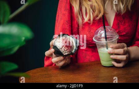 Primo piano torta di ghiaccio e cupcake in un caffè in mani femminili. Foto Stock