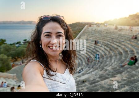 Bella solista signora godendo il tramonto in antico anfiteatro di Kaş. Foto Stock