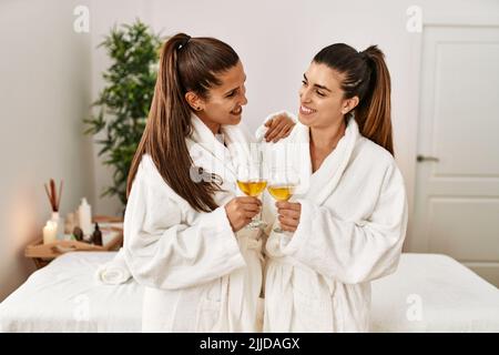 Due donne indossano accappatoio tostando con champagne in piedi al centro di bellezza Foto Stock