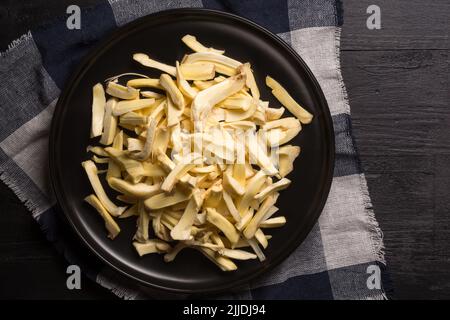 pezzi di carne di jackfruit in un piatto nero, posto su un tavolo nero, frutta benefica per la salute tropicale originaria del sud-est asiatico, preso dall'alto Foto Stock