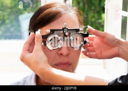 Un oftalmologo seleziona gli occhiali per una donna con un set di lenti di prova. Un paziente su appuntamento di un oftalmologo. Foto Stock