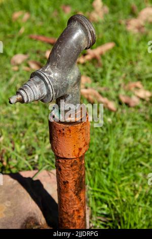 Un vecchio rubinetto d'acqua in ferro chiuso in un parco pubblico. Foto Stock