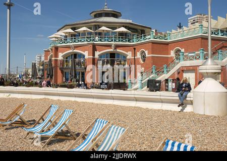 Shelter Hall, recentemente ristrutturato, sul lungomare di Brighton Beach, East Sussex, Inghilterra. Con persone sedute e passeggiando. Foto Stock