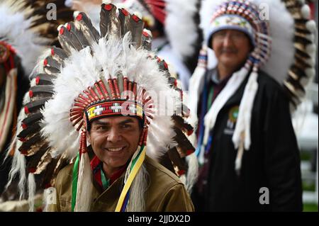 Maskwacis, Canada. 25th luglio 2022. Un nativo canadese che indossa un headdress sorride durante la visita di Papa Francesco come parte della sua gita di più giorni in Canada. Francesco si reca in Canada per incontrare le popolazioni indigene del paese, i cui familiari hanno subito abusi, violenze e umiliazioni nelle scuole di imbarco a conduzione ecclesiastica. Credit: dpa/dpa/Alamy Live News Foto Stock