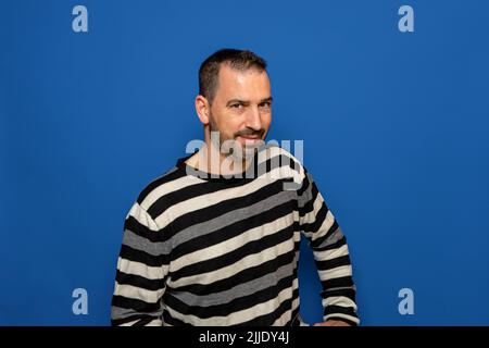Fiducia e concetto di business. Ritratto di affascinante uomo d'affari di successo ispanico indossando un pullover a righe, sorridendo ampiamente con fiducia Foto Stock