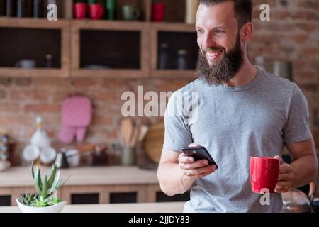 stile di vita dispositivo dipendenza uomo cucina tazza telefono Foto Stock