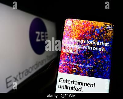 Persona che detiene il cellulare con il sito web della società Zee Entertainment Enterprises Limited sullo schermo con il logo. Concentrarsi sul centro del display del telefono. Foto Stock