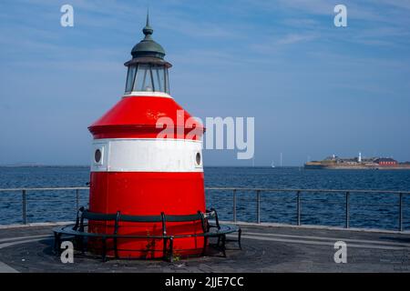 Copenaghen / DANIMARCA - 21 LUGLIO 2022: Un piccolo faro a strisce bianche-rosse sulla riva. Una piccola isola sullo sfondo. Foto Stock