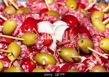 antipasti con salsiccia, olive e mozzarella sugli spiedini. Buffet con tartine e antipasti su spiedini di legno. Salsiccia, olive, mozzarella di se Foto Stock