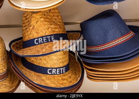 cappelli di paglia in vendita presso un negozio turistico sull'isola greca di creta in grecia, divertenti cappelli di paglia per turisti e vacanzieri in grecia. Foto Stock