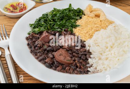 Tipica feijoada brasiliana con riso, pepe, farofa, kale e crackling. Foto Stock