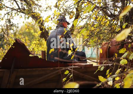 Defocus uomo su vecchio carrello di legno - tempo di raccolta su Ucraina. Foglia verde giallo autunno fuori. Vegetazione colorata nel parco. Caduta foglie naturali. Sfocatura Foto Stock