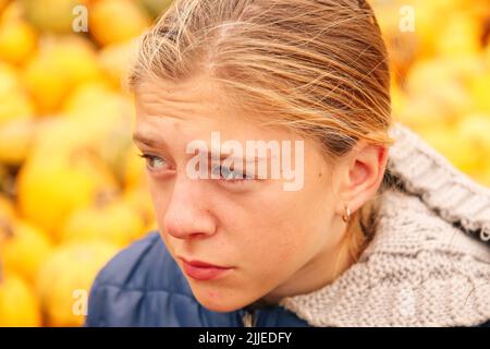 Defocus triste depressa giovane ragazza seduta fuori su sfondo giallo. Scuola, adolescenza, violenza domestica, problemi di amore indesiderati. Solo bambino Foto Stock