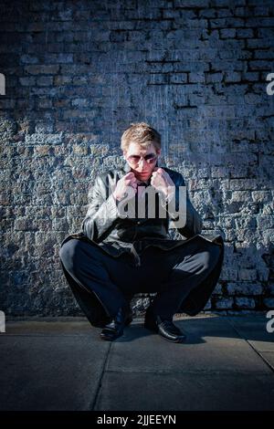 Sottocoperco; sorveglianza. Una spia che si nasconde nelle ombre viene rivelata da un'auto che passa; da una serie di immagini con lo stesso carattere. Foto Stock