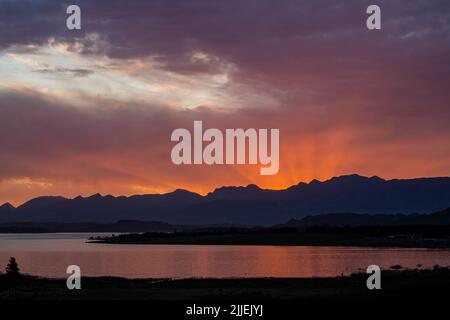 Una bella foto del tramonto arancione sera dietro una montagna Foto Stock