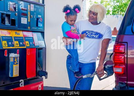 Una donna pompa gas come lei tiene sua figlia, 14 aprile 2011, a Columbus, Mississippi. I prezzi del gas sono aumentati nel 2011 a causa di un indebolimento del dollaro statunitense. Foto Stock