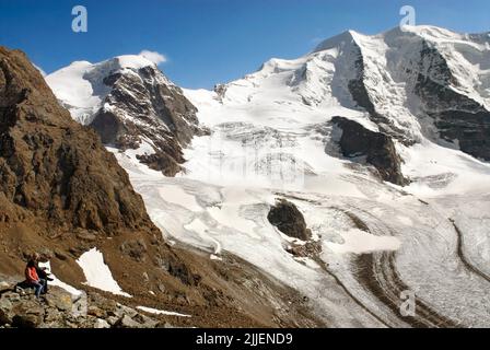 Coppia che guarda il ghiacciaio pers presso la Stazione di montagna Diavalezza, Pontresina, Svizzera, Grigioni, Engadina, Pontresina Foto Stock