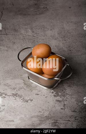 uovo di pollo su un cestello di metallo e sfondo grigio Foto Stock