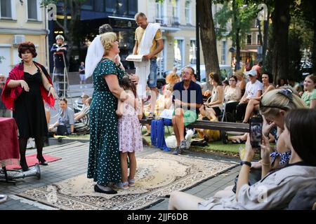 Odessa, Ucraina. 23rd luglio 2022. Il pubblico guarda come attori teatrali eseguire 'Odessa, io ti amo' al mercato del libro a Odessa. Lo spettacolo 'Odessa, ti amo' racconta storie della vita degli abitanti di Odessa con il suo caratteristico colore e umorismo. Lo spettacolo è stato organizzato dagli attori del Teatro n° 7 e giocato all'aperto al mercato del libro. L'obiettivo della performance è quello di aumentare le donazioni per le esigenze di difesa aerea. (Foto di Viacheslav Onyshchenko/SOPA Images/Sipa USA) Credit: Sipa USA/Alamy Live News Foto Stock