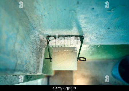 Un rotolo della carta igienica a velo singolo più economica su un supporto di carta igienica in un bagno rurale all'aperto Foto Stock