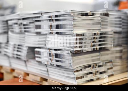 Soft focus di fogli di cataloghi appena stampati impilati su pallet di legno in laboratorio tipografico Foto Stock