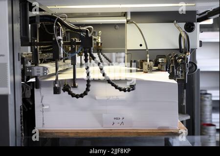 Caricamento automatico a macchina di una pila di fogli di carta in una stampante offset industriale in officina tipografica Foto Stock
