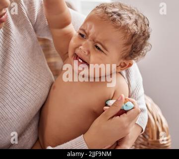 Le mamme ti hanno sempre preso. Un bambino piangendo mentre ha la sua temperatura controllata da sua madre. Foto Stock