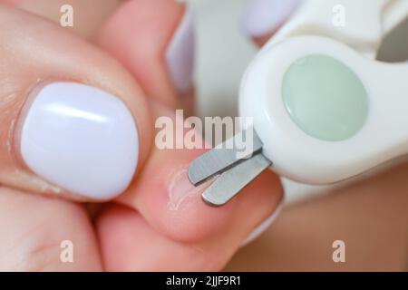 Una madre taglia le unghie di un bambino piccolo, età un anno. Taglio capelli per un bambino, foto macro Foto Stock