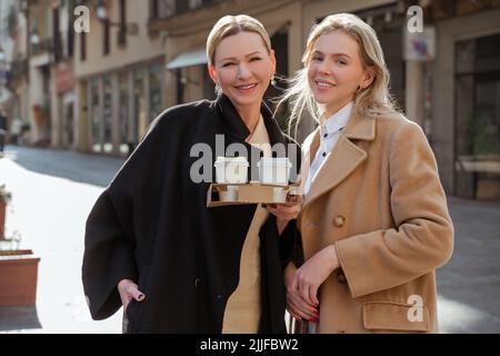 Donne allegre ed eleganti che posano per la macchina fotografica in strada Foto Stock