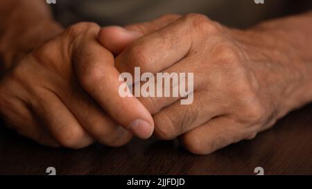 Mani dell'uomo più anziano sul tavolo in primo piano Foto Stock