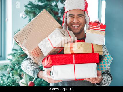 Forse ho bisogno di più mani, un giovane che tiene i suoi regali di Natale a casa. Foto Stock